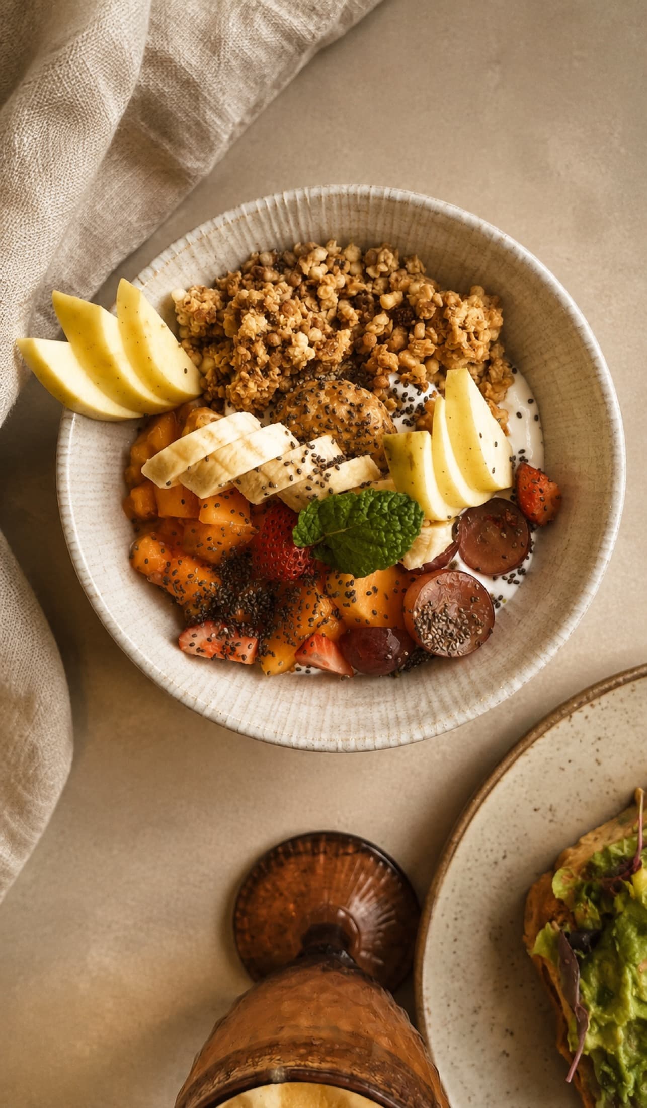 Bol de fruits frais, granola et graines de chia sur une nappe de lin